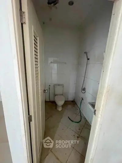 Compact bathroom with basic fixtures and tiled walls, ideal for renovation.