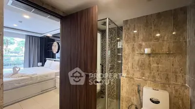 Modern bedroom with ensuite bathroom featuring glass shower and elegant decor.