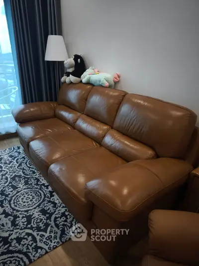 Luxurious brown leather sofa in a cozy living room with plush toys and elegant decor.