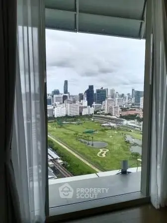 Stunning cityscape view from high-rise apartment window overlooking lush green golf course.