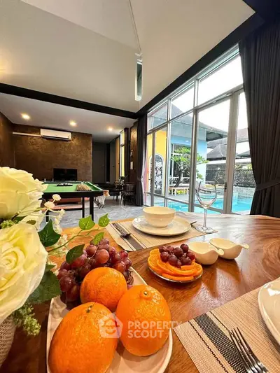 Luxurious living room with pool view, elegant dining setup, and modern decor.