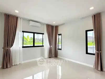 Spacious empty room with large windows and elegant curtains, offering a bright and airy atmosphere.