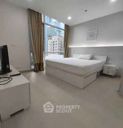 Modern bedroom with city view, featuring sleek furniture and large windows.