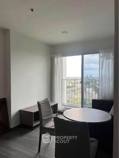 Cozy living room with round table and chairs, offering a scenic city view through large windows.