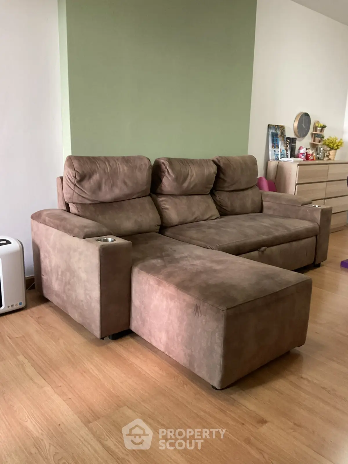 Spacious living room with a cozy brown sectional sofa and wooden flooring, perfect for relaxation.