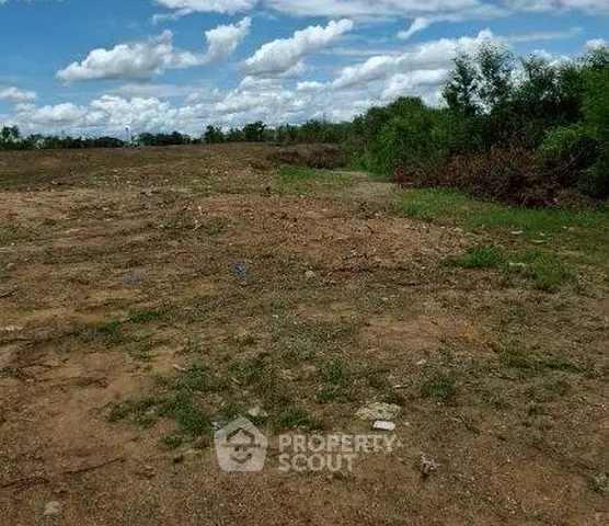 Expansive vacant land with lush greenery and clear skies, perfect for development opportunities.