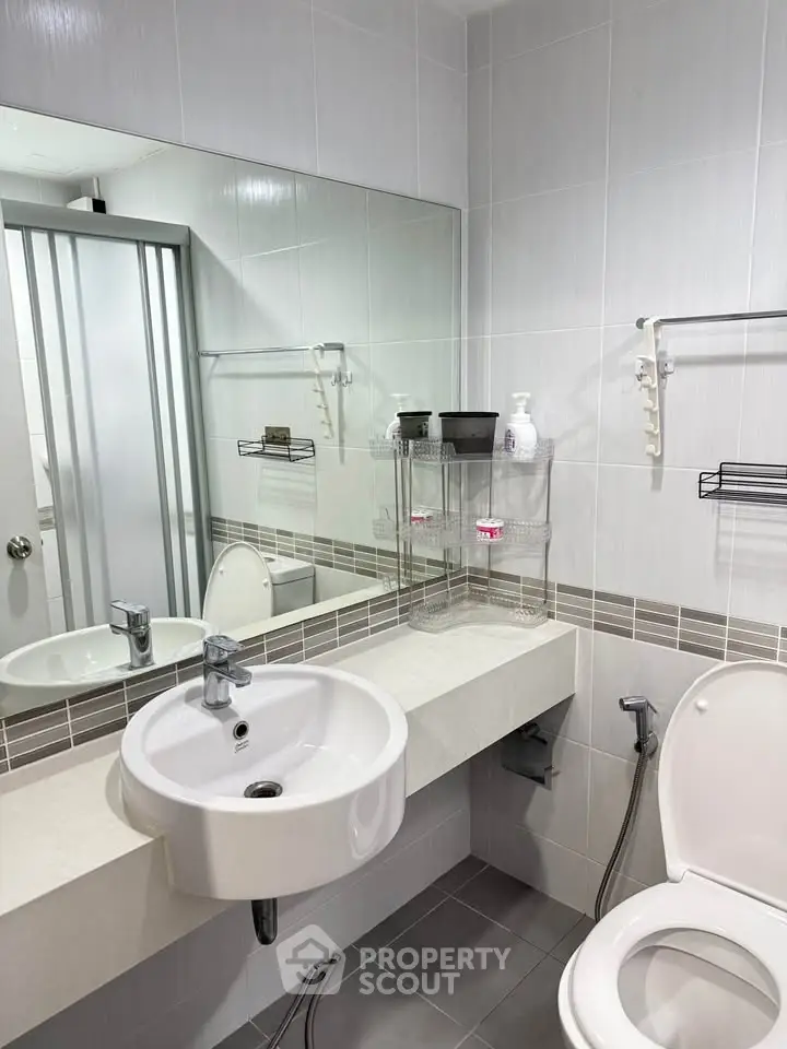 Modern bathroom with sleek fixtures and spacious mirror in contemporary apartment.