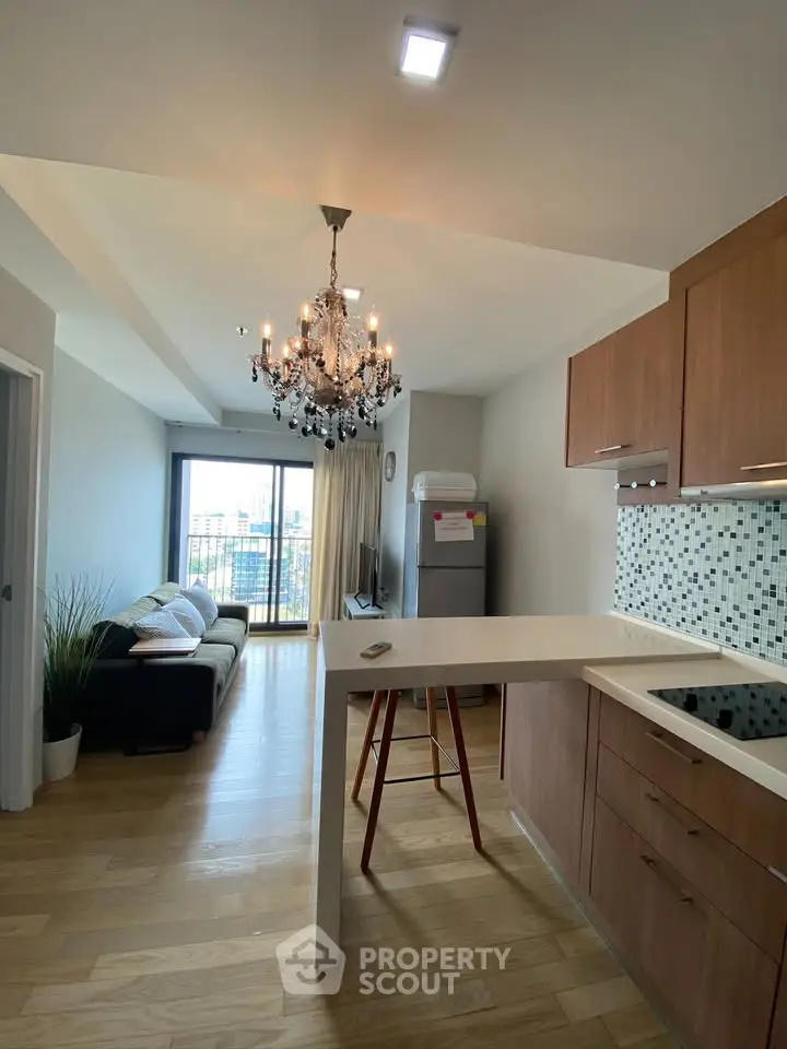 Modern open-layout kitchen and living room with chandelier and balcony view