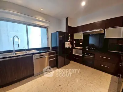 Modern kitchen with sleek dark cabinets, stainless steel appliances, and spacious layout.