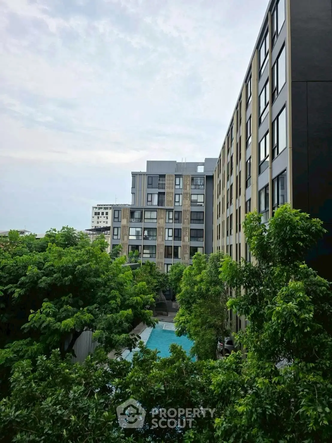 Modern apartment building with lush greenery and pool view