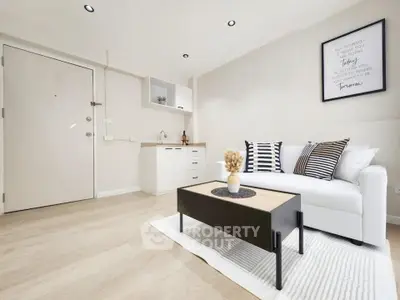 Modern living room with stylish decor and compact kitchenette, featuring a cozy white sofa and elegant coffee table.