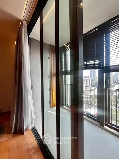 Modern apartment with floor-to-ceiling windows and city view from balcony.