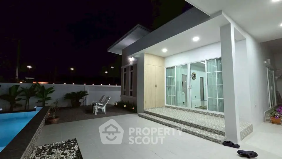 Modern exterior view of a stylish home with pool and patio lighting at night.