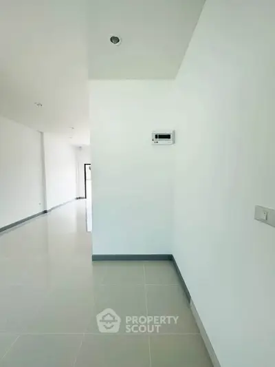 Spacious minimalist interior with white walls and tiled flooring, perfect for customization.