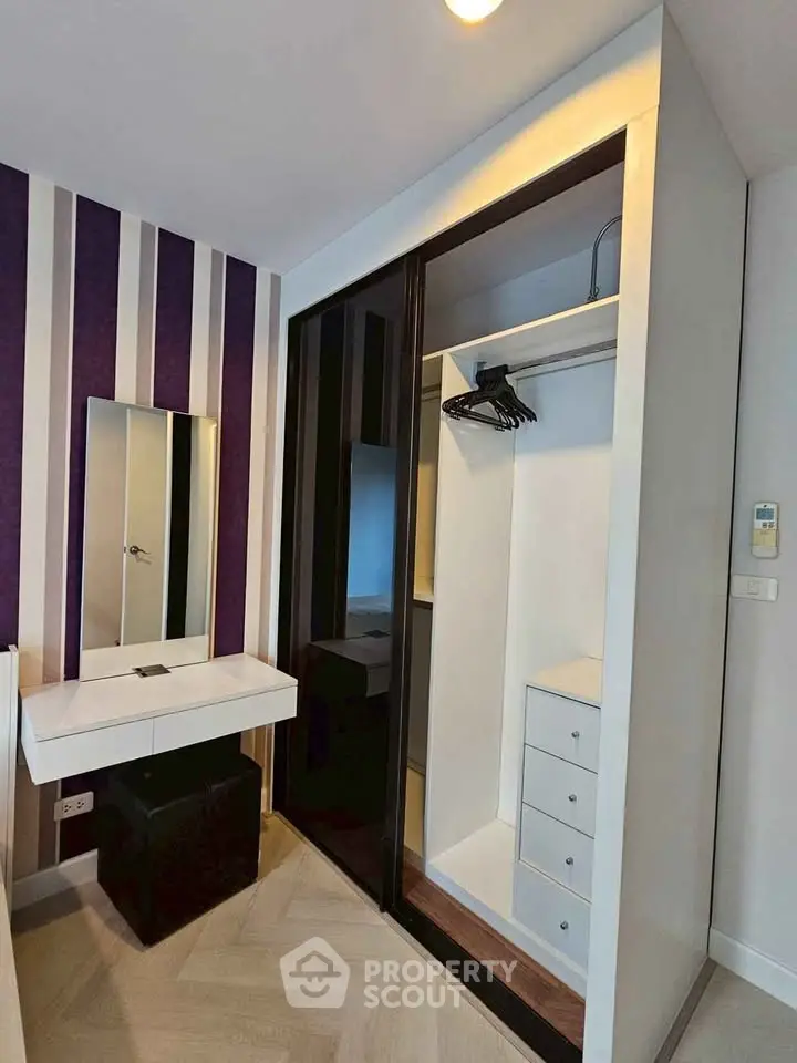 Modern bedroom with stylish closet and vanity area, featuring sleek design and ample storage space.