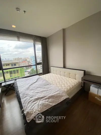 Spacious bedroom with large window offering city views, featuring a comfortable bed and modern decor.