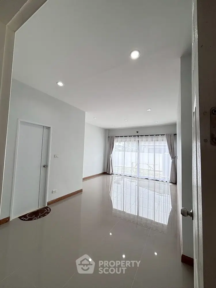 Spacious empty room with glossy tiled floor and large window for natural light.