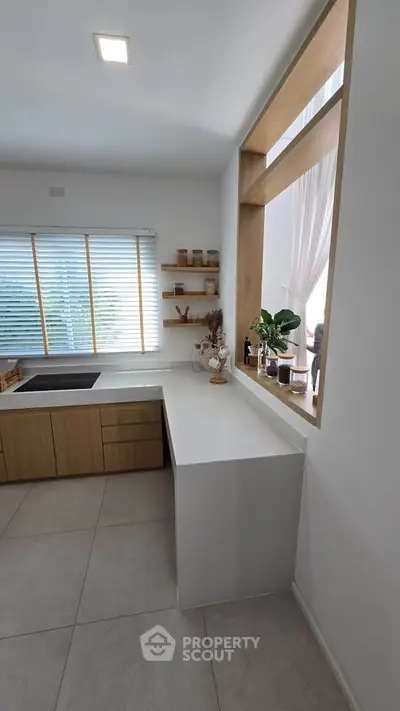 Modern kitchen with sleek design and open layout, featuring wooden cabinets and large window.