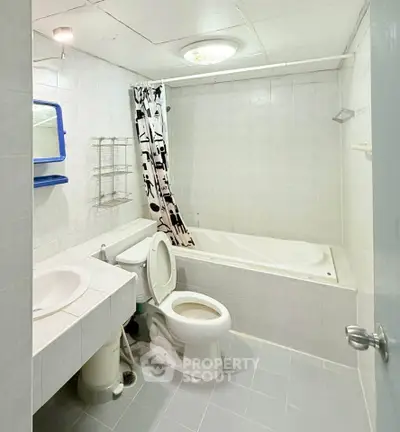 Spacious bathroom with bathtub and modern fixtures in a bright, tiled setting.