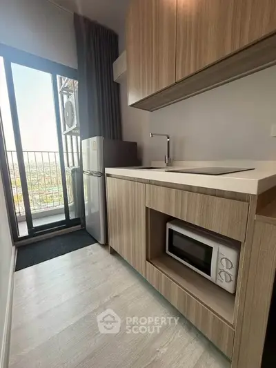 Modern kitchen with sleek cabinetry and balcony view in high-rise apartment