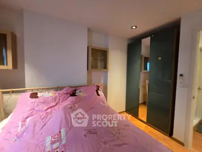 Cozy bedroom with pink bedding and modern wardrobe in stylish apartment.