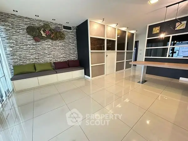 Modern living room with stylish decor and open layout, featuring tiled flooring and contemporary seating.