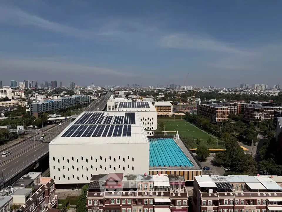 Aerial view of modern building complex with solar panels and swimming pool.