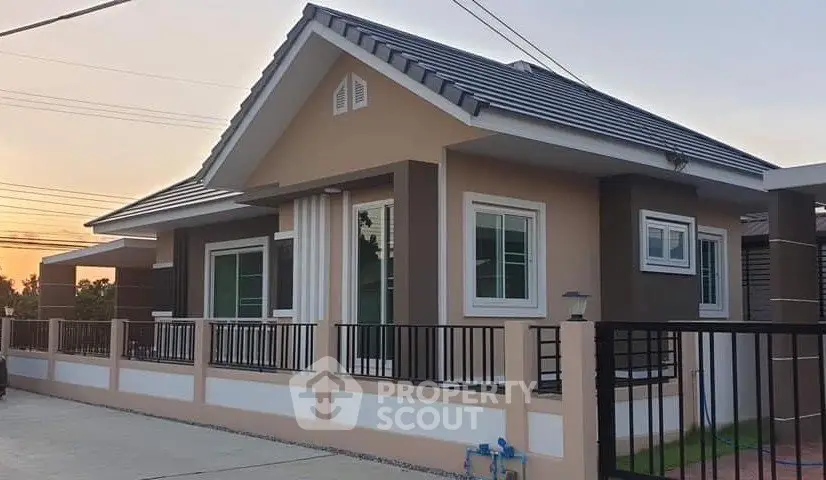 Charming single-story house with modern design and fenced yard at sunset.