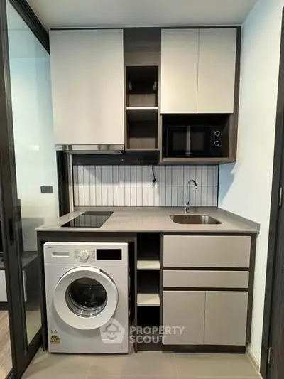 Modern compact kitchen with built-in appliances and washing machine in sleek design.