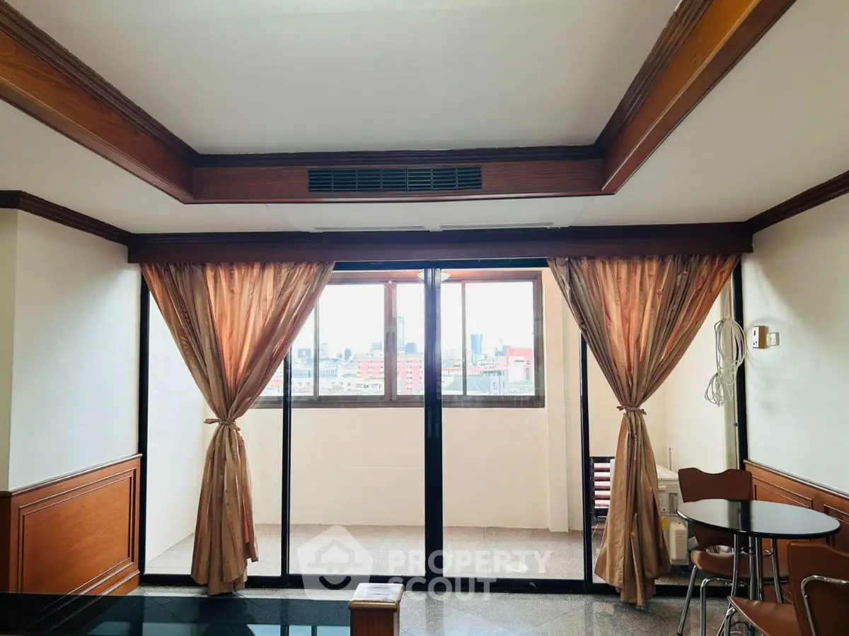 Spacious room with large windows and city view, featuring elegant curtains and wooden accents.