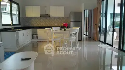 Spacious modern kitchen with open layout and dining area, featuring sleek white cabinets and stainless steel appliances.