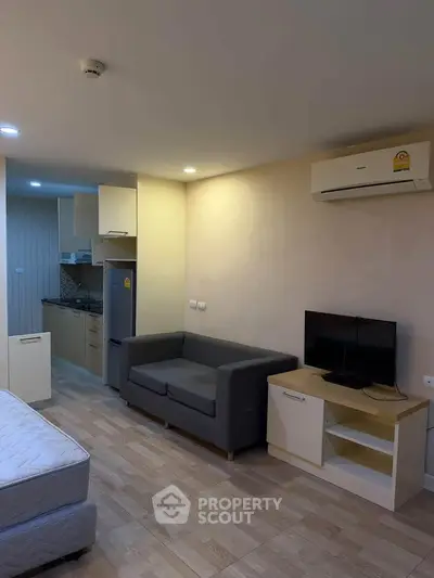 Modern studio apartment with open layout, featuring a cozy living area and compact kitchen.