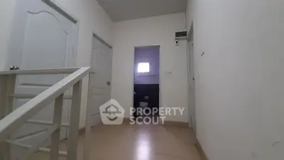 Spacious hallway with wooden flooring and multiple doors leading to rooms.