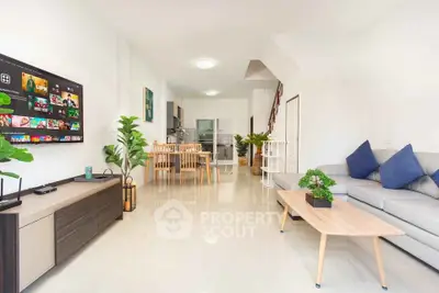Spacious modern living room with open kitchen, stylish decor, and natural light.