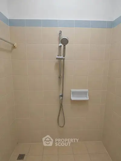 Minimalist bathroom shower area with beige tiles and modern fixtures.