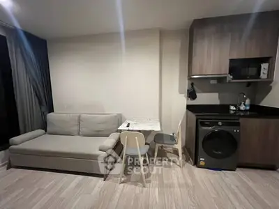 Modern compact living room with sofa, dining table, and kitchen appliances.