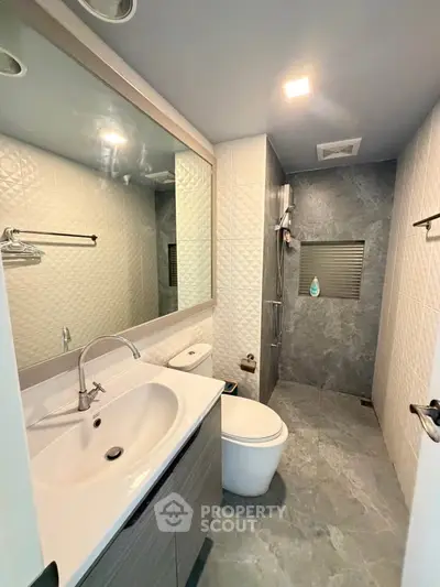 Modern bathroom with sleek design, featuring a spacious shower and elegant vanity.