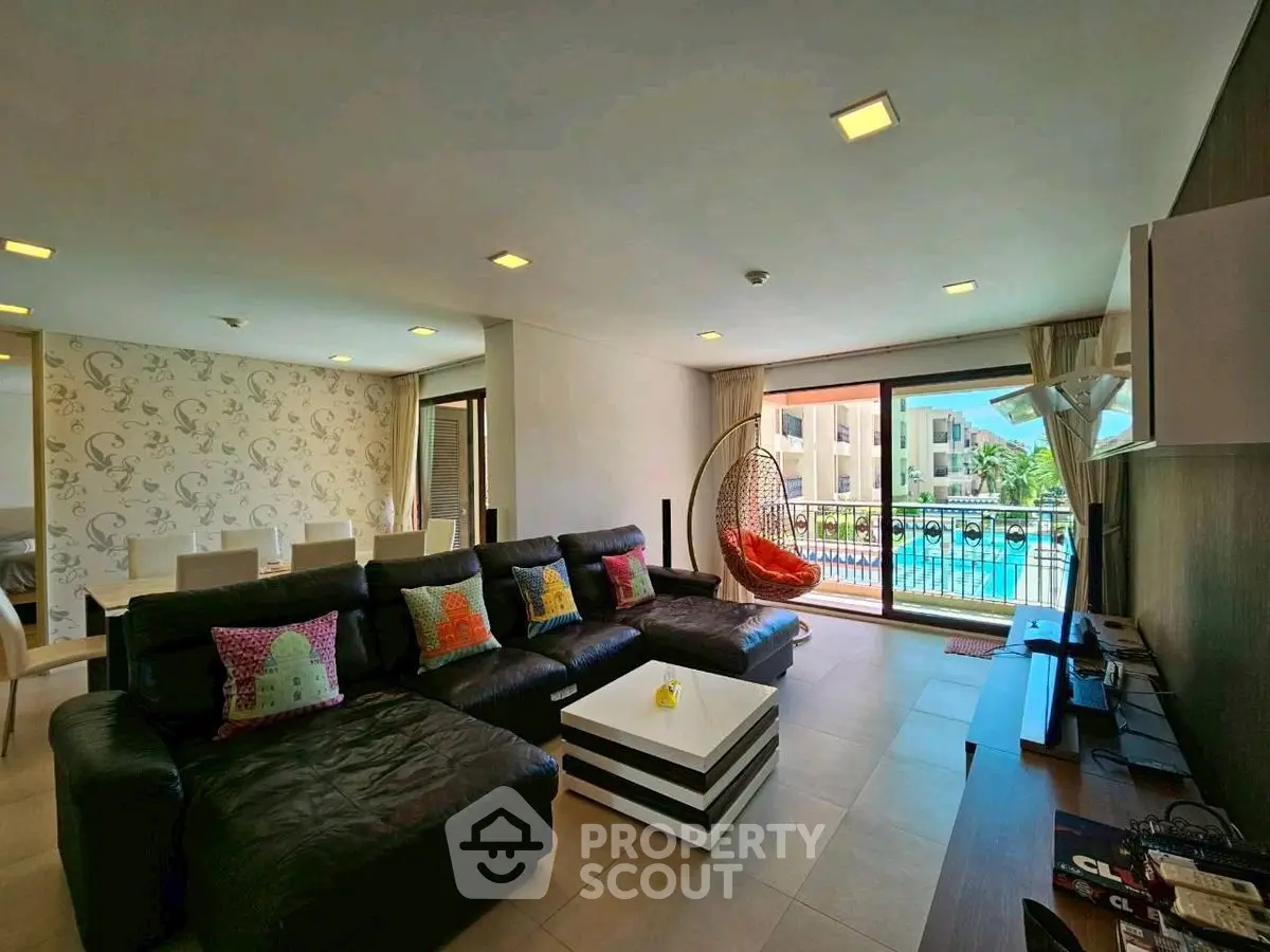 Spacious living room with pool view, modern decor, and large balcony access.