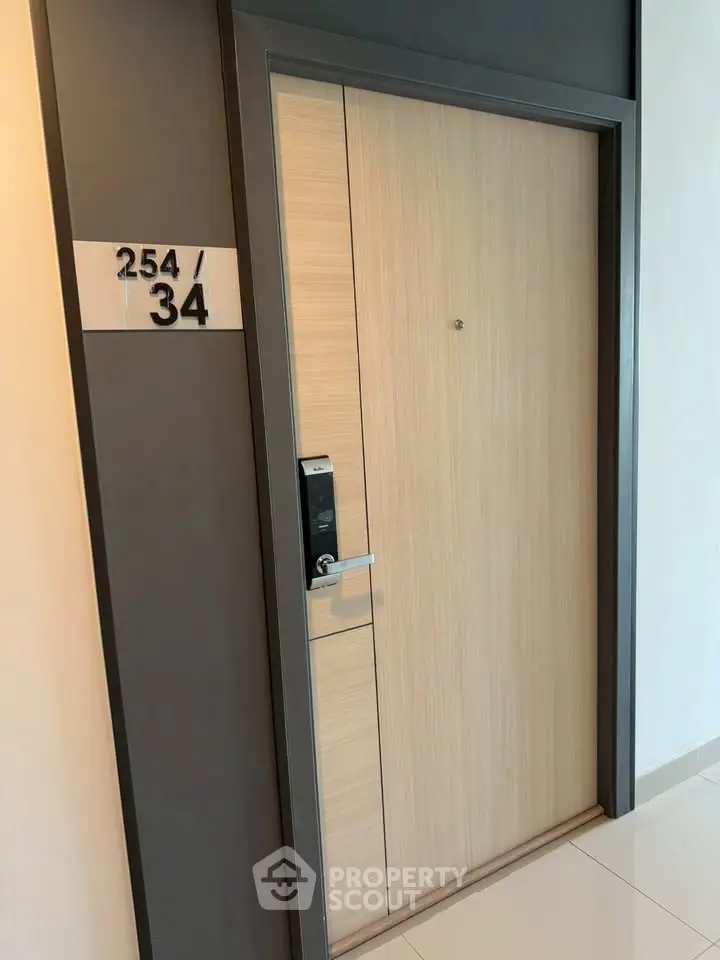 Modern apartment entrance with sleek wooden door and digital lock system.