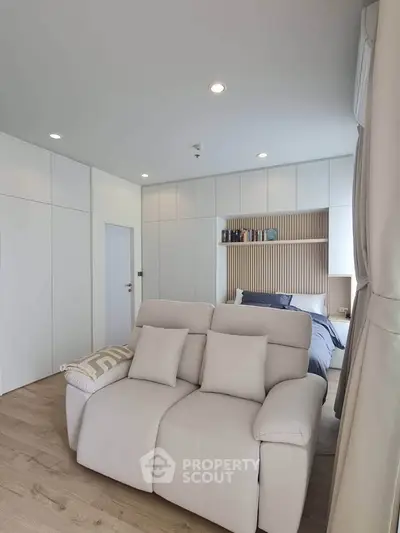 Modern bedroom with cozy seating and stylish decor, featuring built-in storage and soft lighting.