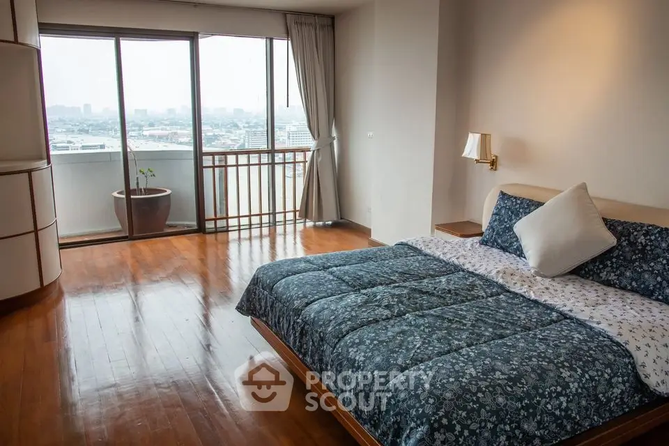 Spacious bedroom with large windows and city view, featuring elegant wooden flooring and modern decor.