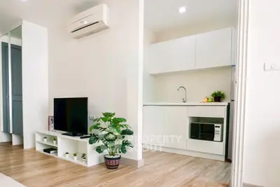 Modern studio apartment with sleek kitchen and cozy living area, featuring air conditioning and stylish decor.