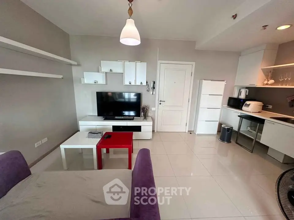 Modern living room with sleek kitchen, white cabinets, and cozy seating area in open layout apartment.