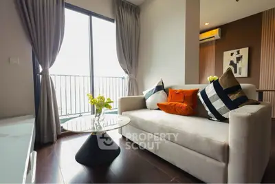 Modern living room with stylish sofa, elegant decor, and large window offering natural light and city view.