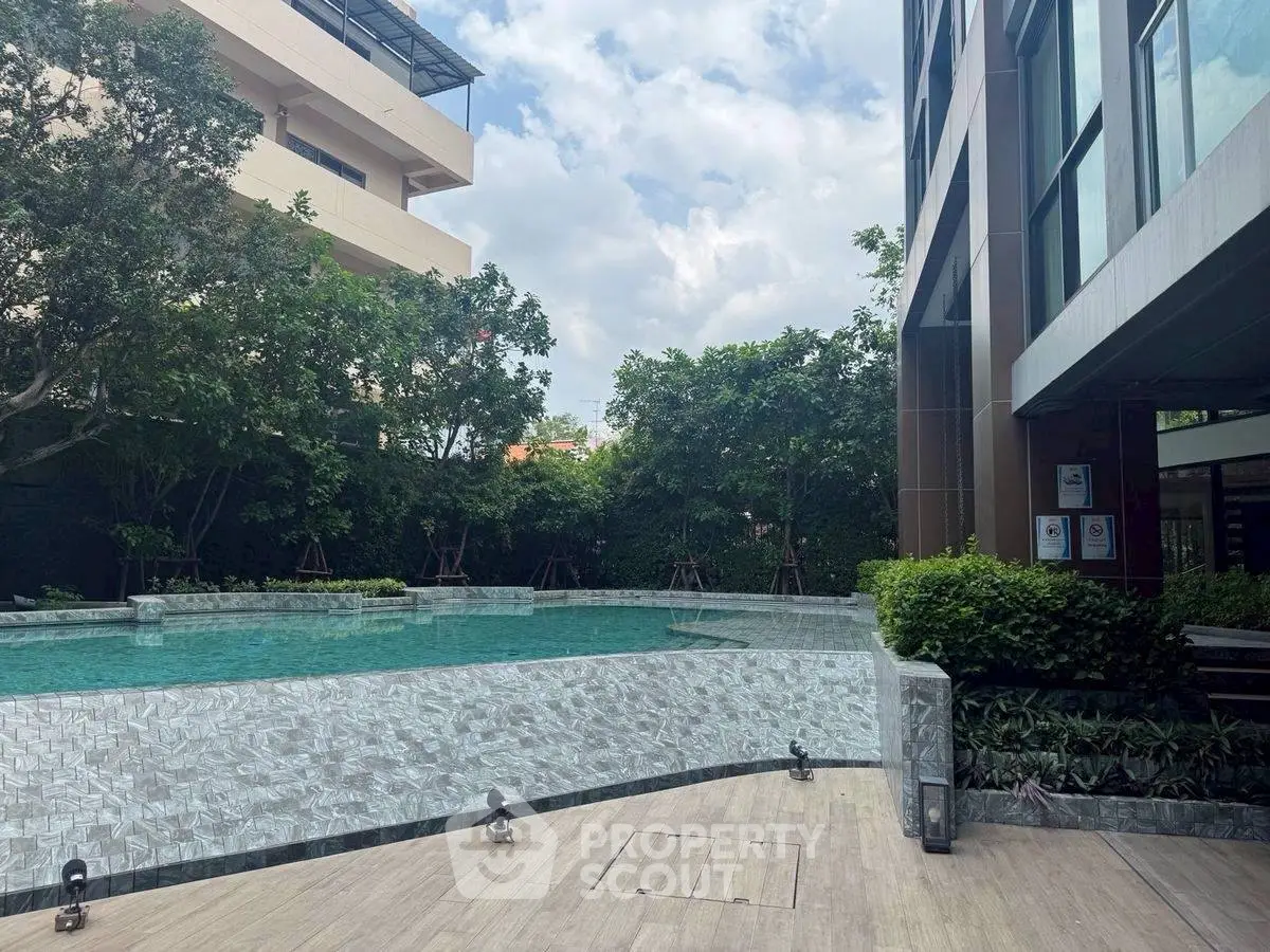 Luxurious residential pool area with lush greenery and modern architecture.