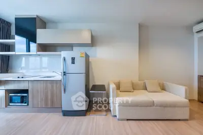 Modern open-layout living room with kitchen, featuring sleek appliances and cozy sofa.