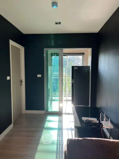 Modern apartment interior with sleek black walls and balcony access, featuring natural light and contemporary design.