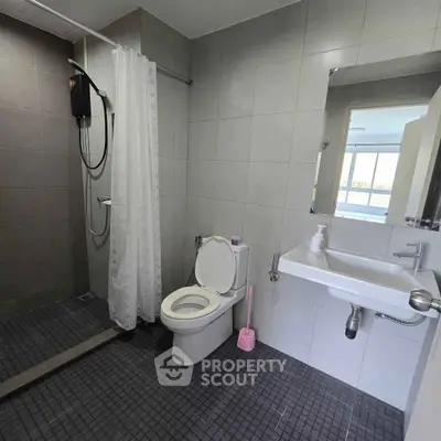 Modern bathroom with shower, toilet, and sink in a sleek tiled design.