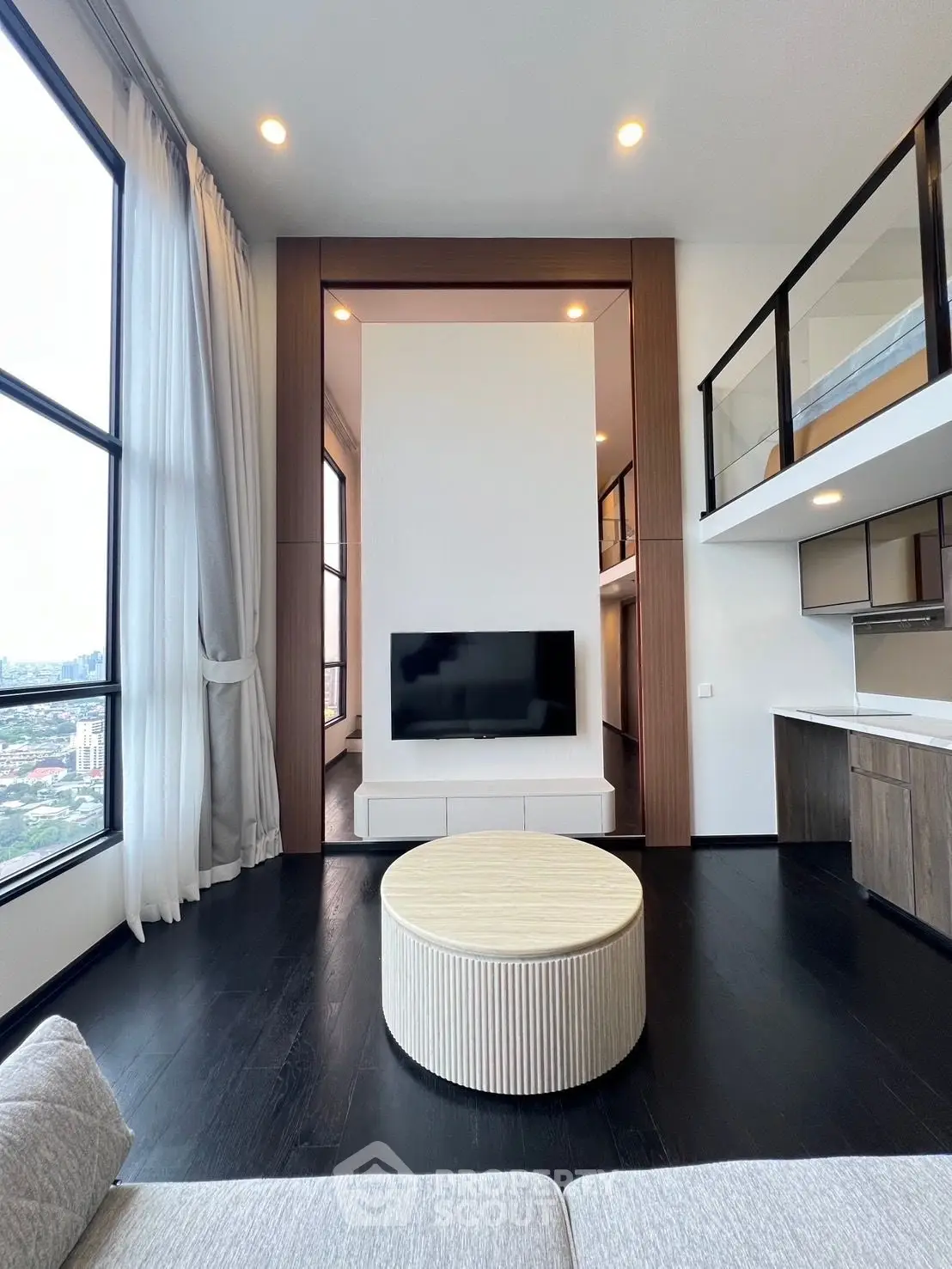 Modern loft-style living room with high ceilings and large windows offering city views.