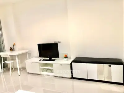 Modern living room with sleek white furniture and a flat-screen TV, perfect for minimalist living.